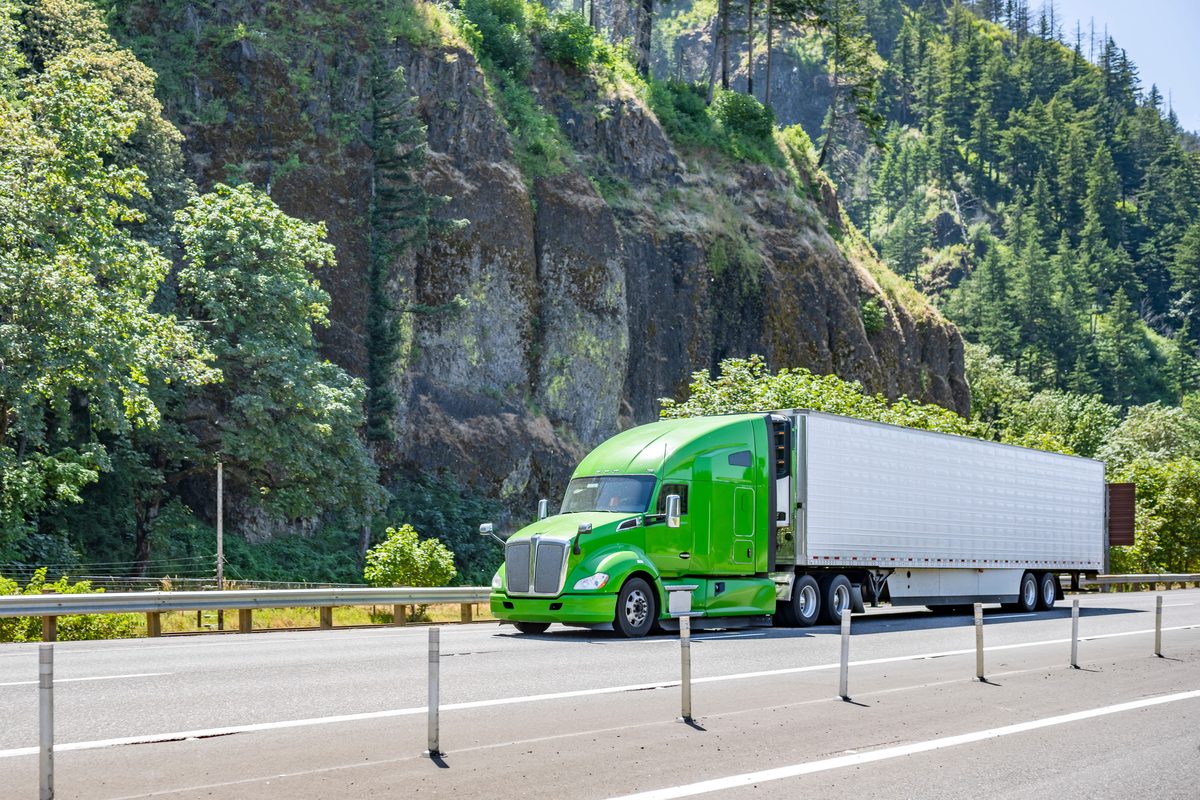 Green semi-truck hauling a trailer on a highway